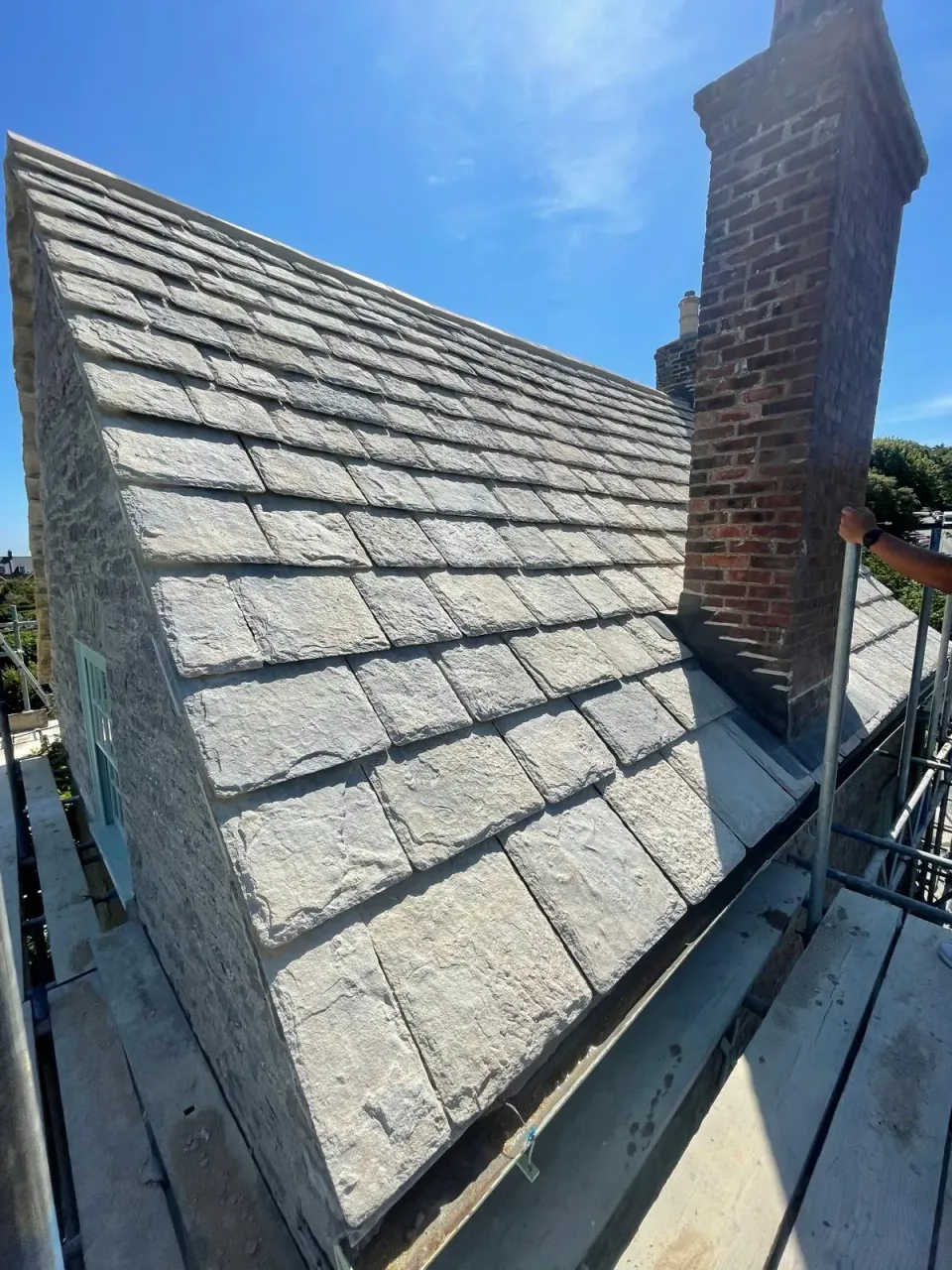 View along the stone roof and gutter towards the chimney with scaffold access still in place