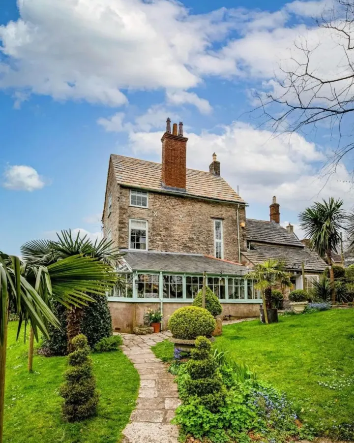 Garden view of the listed stone house in Swanage with its completed Purbeck stone roof