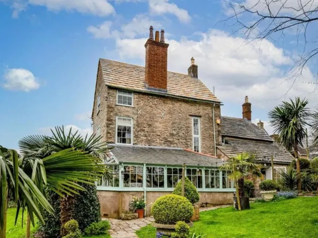 Garden view of the listed stone house in Swanage with its completed Purbeck stone roof