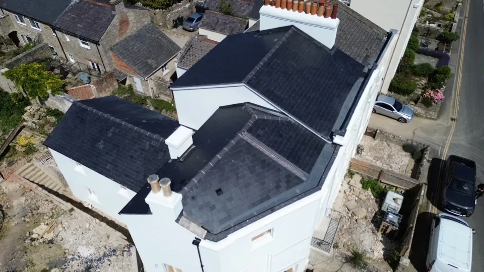 Aerial view of traditional lead mop roll details on a natural slate roof in Swanage