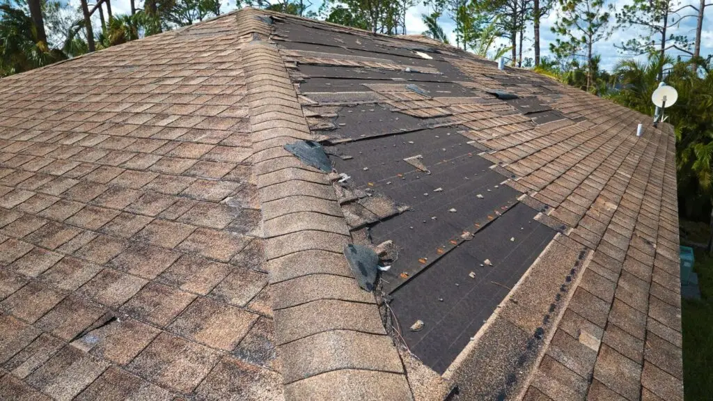 Close-up of a pitched roof with several missing and cracked tiles, exposing the underlayment and highlighting the need for tile replacement.